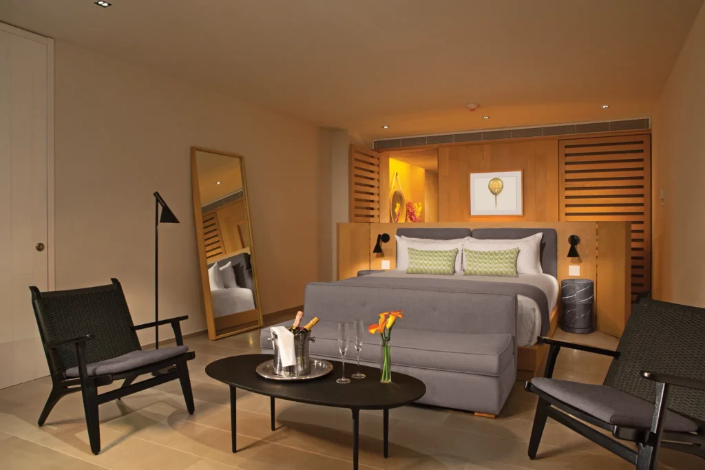 Allure Suite bedroom and living area at Breathless Cabo San Lucas with king bed, seating space, and modern décor