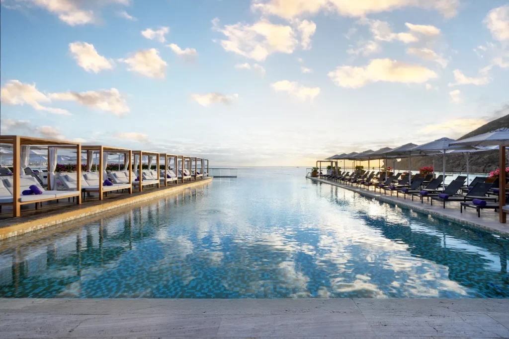 Infinity pool at Breathless Cabo Beach Club overlooking the ocean with cabanas and loungers on both sides.