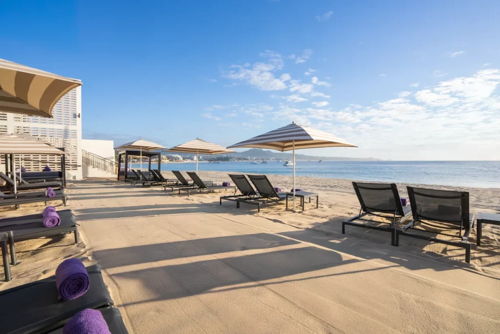 Oceanfront loungers and umbrellas on the beach at Breathless Cabo San Lucas Resort.