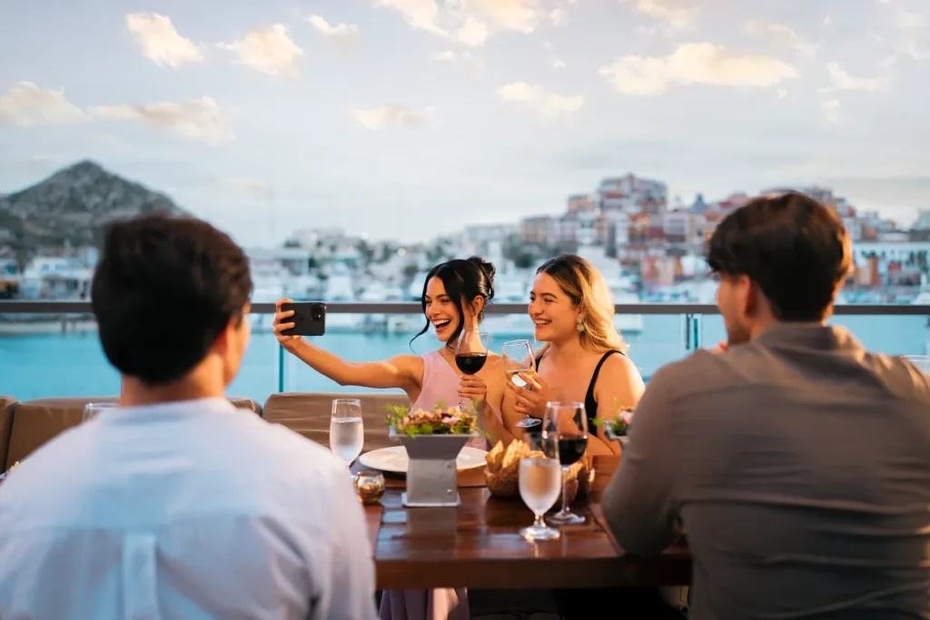Guests taking a selfie while enjoying wine at an oceanview restaurant at Breathless Cabo San Lucas.