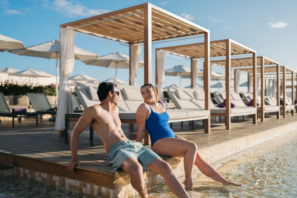 Couple relaxing by the pool with luxury cabanas at Breathless Cabo San Lucas.