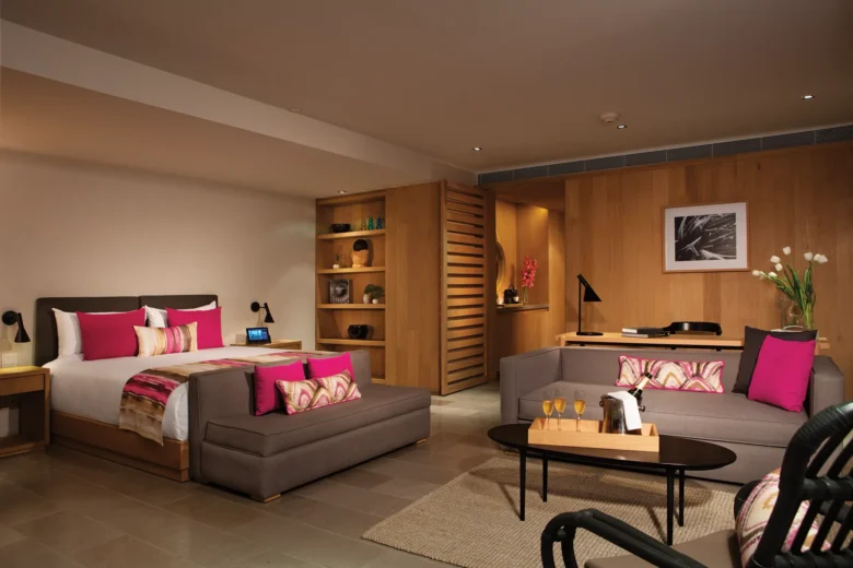 Spacious bedroom and living area of the Xhale Club Romance Suite Marina View at Breathless Cabo San Lucas with modern décor and vibrant accents.