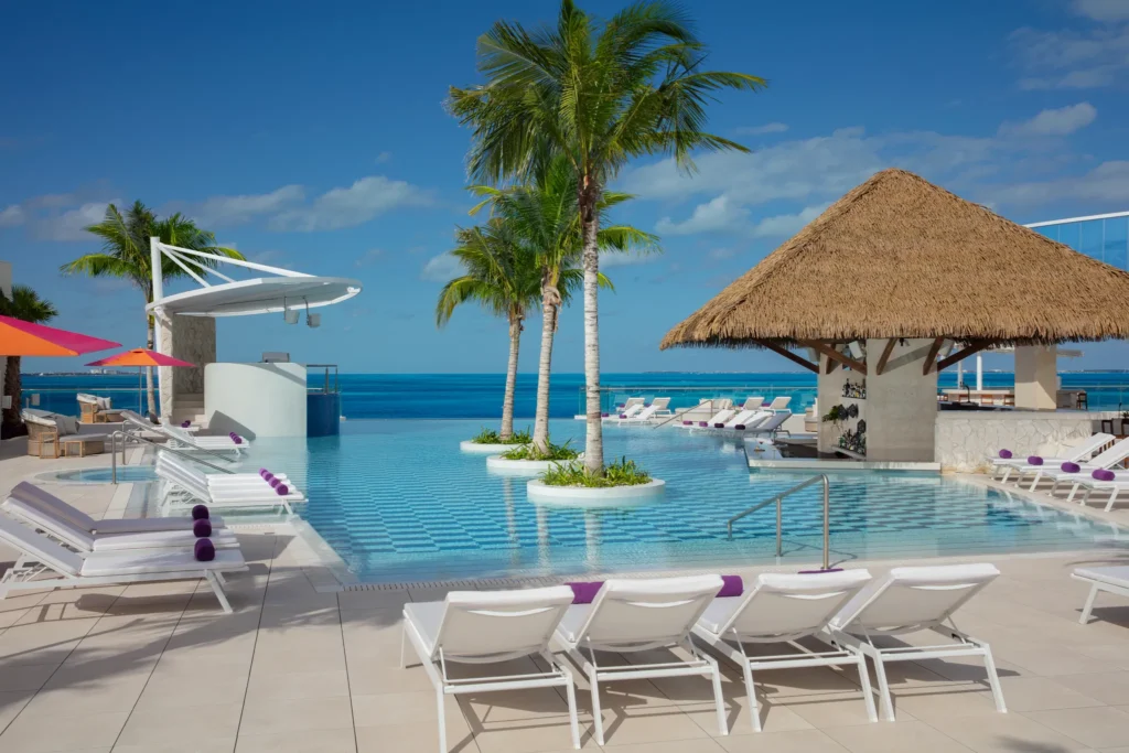 Oceanfront pool and Deep Bar at Breathless Cancun Soul Resort with lounge chairs and palm trees.