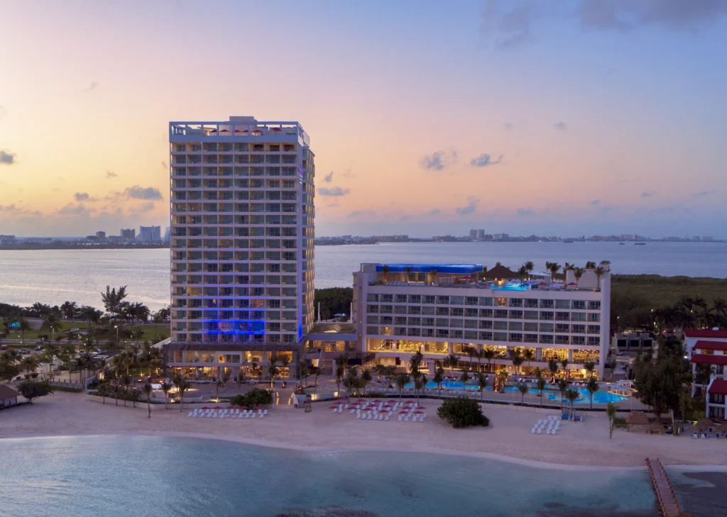 Aerial night view of Breathless Cancun Soul Resort illuminated along the Caribbean coastline.