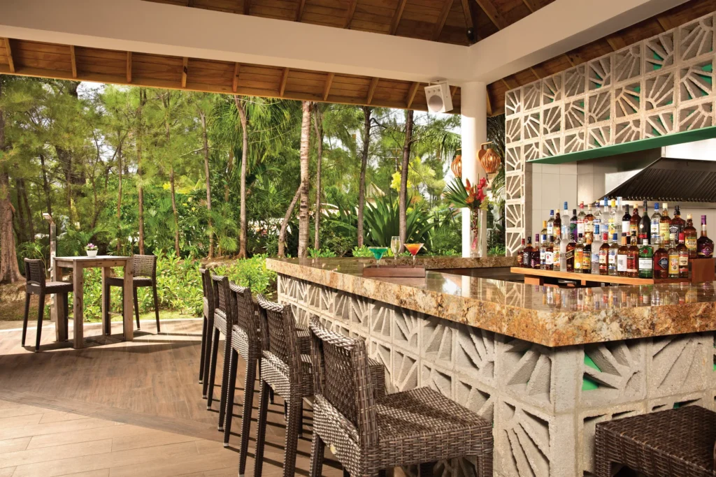 Tropical outdoor bar at Foam Beach Bar at Breathless Montego Bay surrounded by lush greenery.