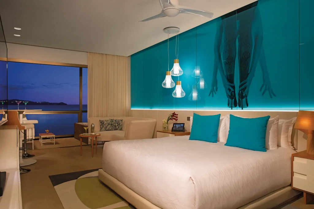 Night view of the Xhale Club Junior Suite Ocean View at Breathless Montego Bay with ambient blue lighting and balcony overlooking the bay.