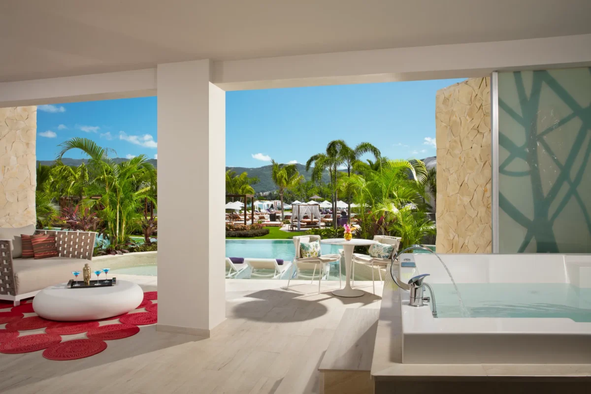 Private swim-out terrace of the Xhale Club Master Suite at Breathless Montego Bay featuring direct pool access, outdoor seating, tropical landscaping, and a soaking tub.