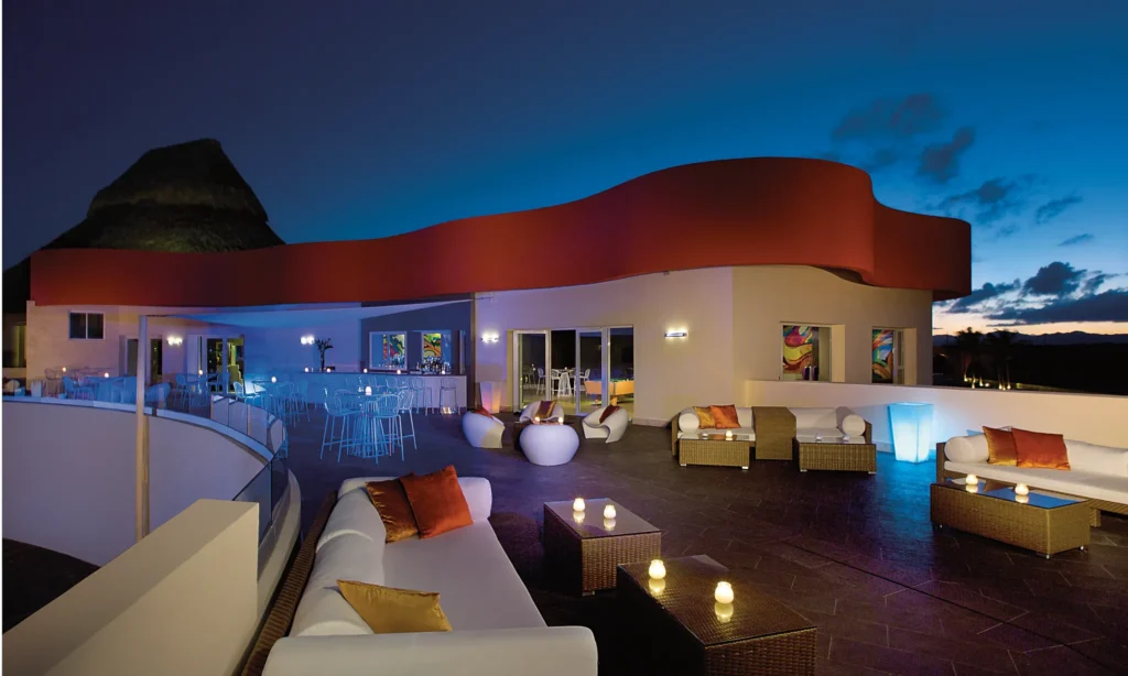 Showstopper theater bar at Breathless Punta Cana featuring modern lounge seating, ambient evening lighting, and an open-air entertainment setting.