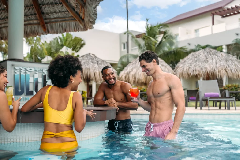 Friends socializing at a swim-up bar at Breathless Punta Cana with tropical drinks.