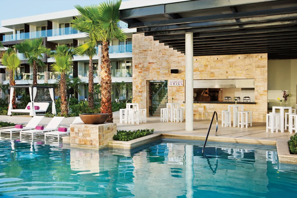 Barefoot Grill outdoor dining area next to the pool at Breathless Riviera Cancun with casual seating and tropical landscaping.