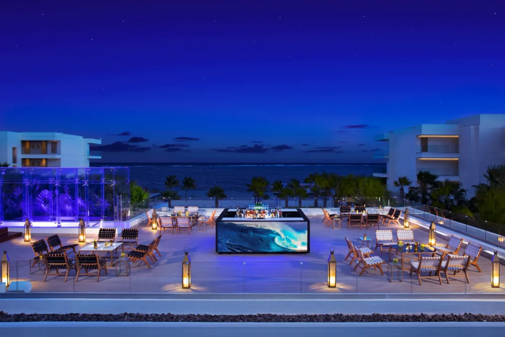 Evening cocktail event on the rooftop terrace at Breathless Riviera Cancun with ocean views, lantern lighting, and lounge seating.
