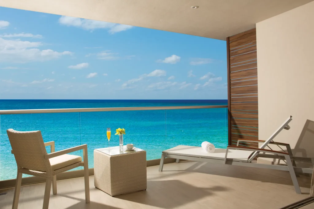 Private oceanfront terrace of the Xcelerate Junior Suite at Breathless Riviera Cancun featuring lounge chairs and panoramic Caribbean Sea views.