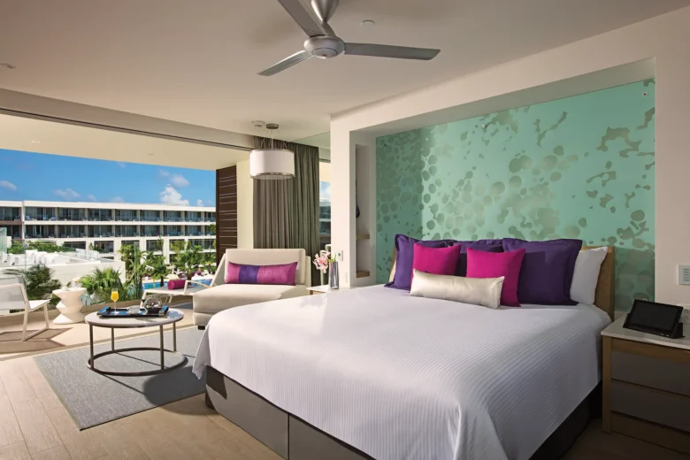 Ocean view bedroom in the Xhale Club Junior Suite at Breathless Riviera Cancun featuring a king bed, modern décor, sitting area, and private balcony with ocean views.