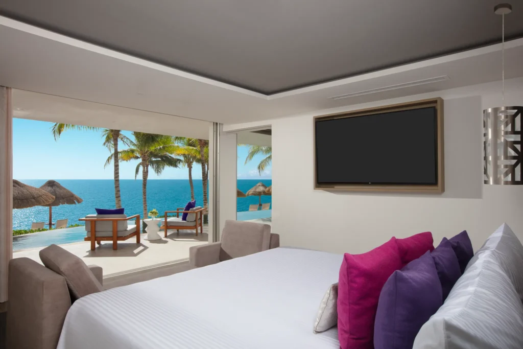 Xhale Club Presidential Suite Swim Out Ocean Front bedroom at Breathless Riviera Cancun with king bed, floor-to-ceiling windows, and direct access to a private swim-out pool overlooking the Caribbean Sea.