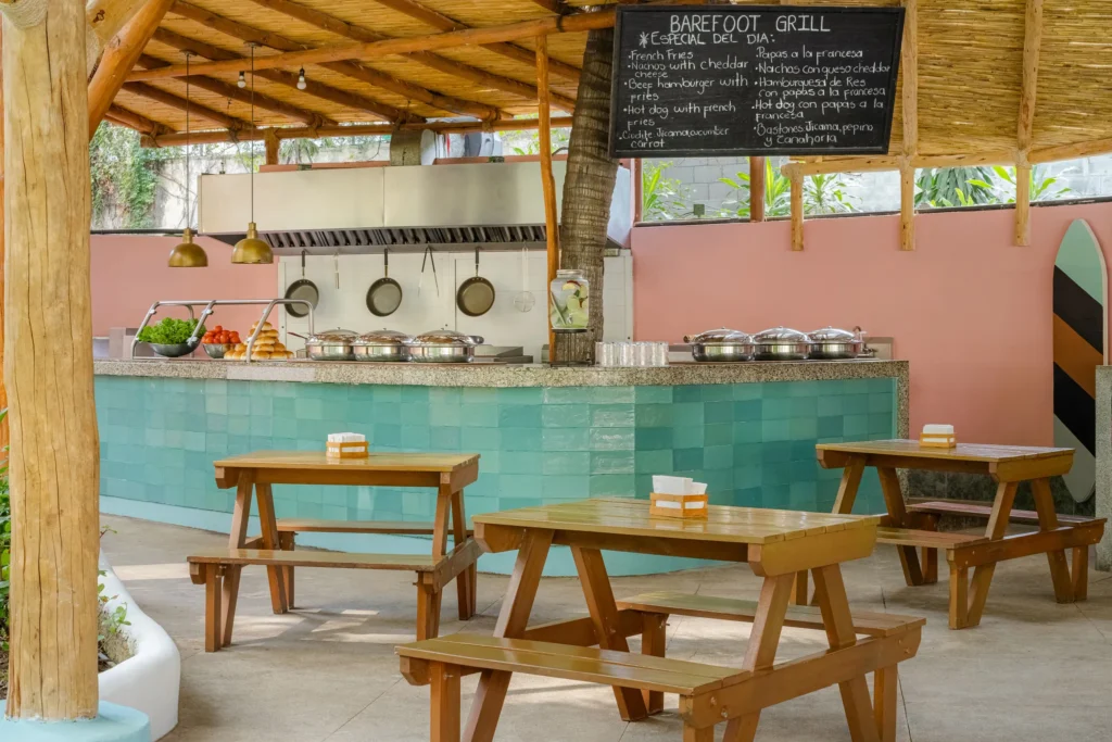 Barefoot Grill at Dreams Acapulco Resort & Spa featuring a casual poolside dining area with wooden picnic tables and an open-air grill station.