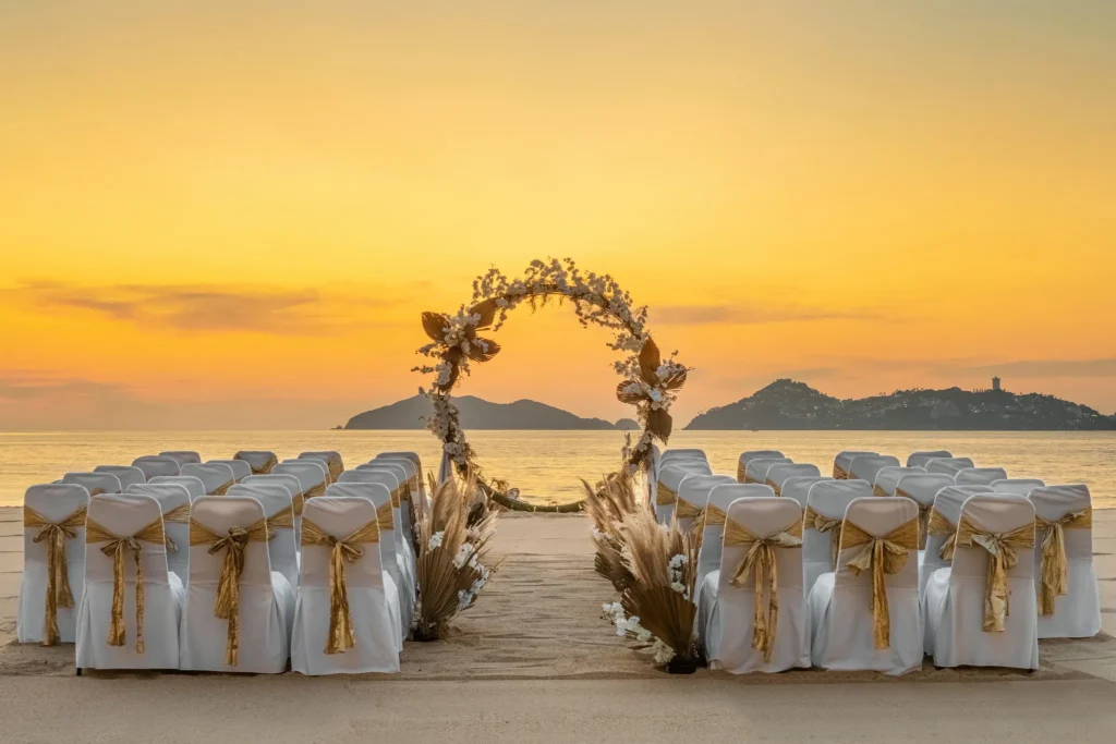 Beach wedding ceremony setup with floral arch at sunset at Dreams Acapulco Resort & Spa