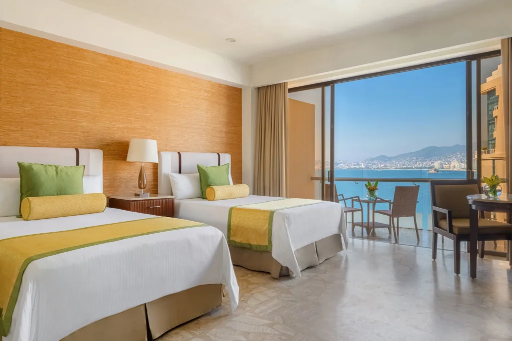 Deluxe Partial Ocean View guest room with two double beds and bay views at Dreams Acapulco Resort & Spa.