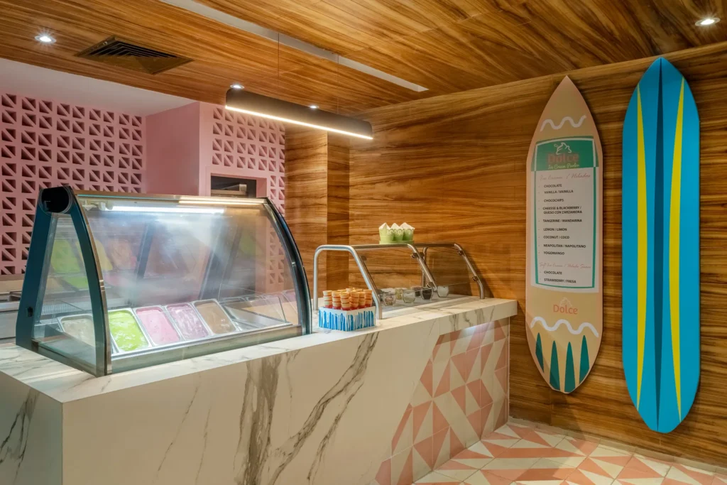 Dolce Ice Cream Parlor at Dreams Acapulco Resort & Spa featuring a colorful gelato display, marble counter, and casual dessert setting.