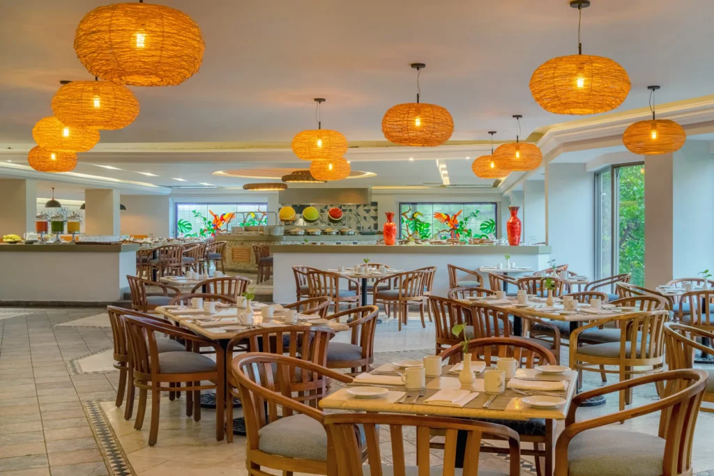 La Ceiba International Buffet at Dreams Acapulco Resort & Spa featuring elegant dining tables, warm woven pendant lighting, and buffet stations with global cuisine.