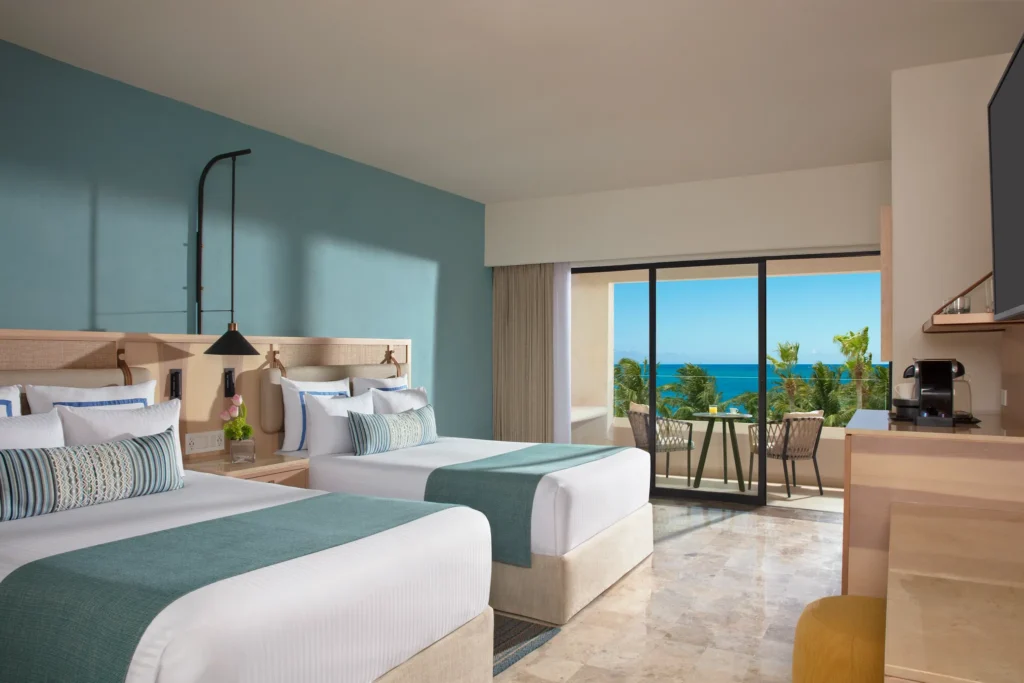 Deluxe Ocean View room with two double beds and balcony overlooking the ocean at Dreams Aventuras Riviera Maya.