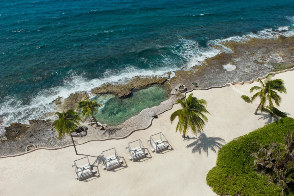 Natural ocean-fed pool with rocky shoreline and clear turquoise water at Dreams Aventuras Riviera Maya.