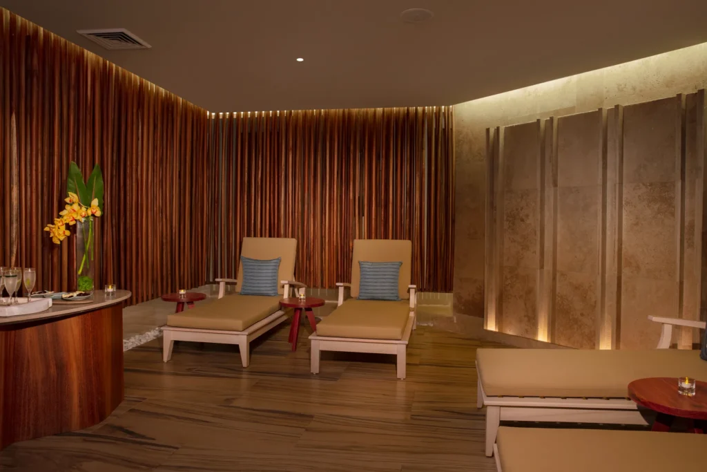 Indoor spa relaxation lounge with cushioned chairs and warm wood accents at Dreams Aventuras Riviera Maya.