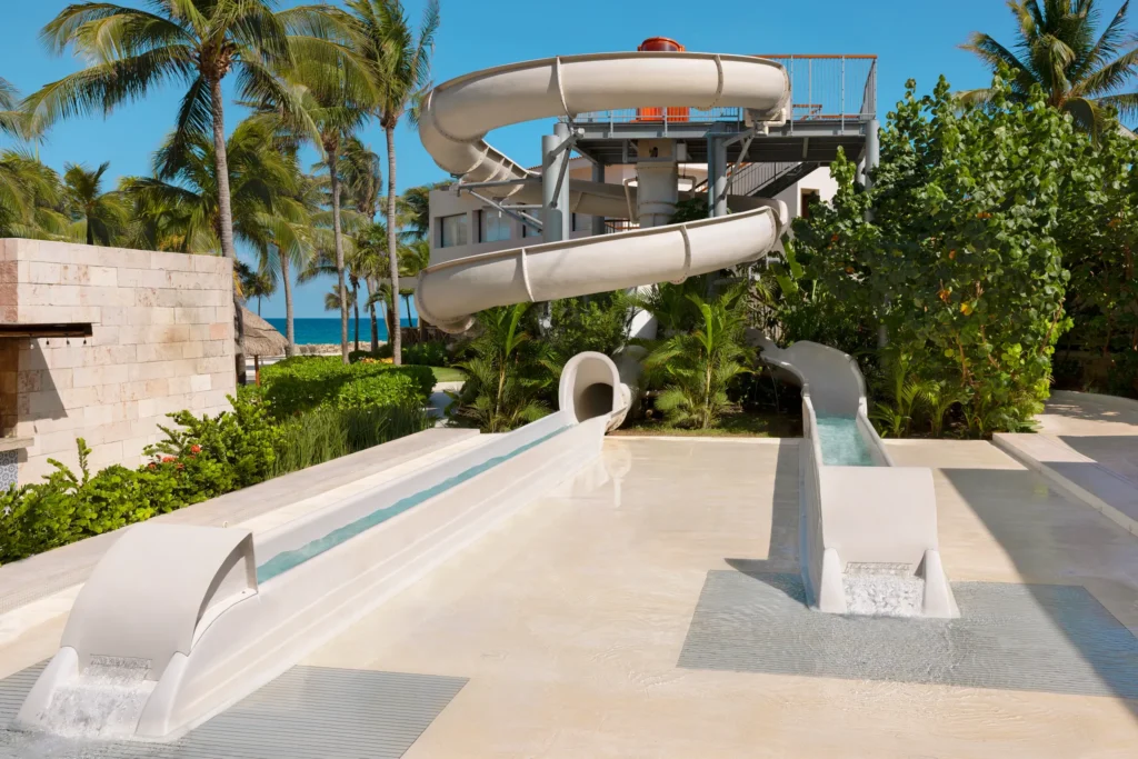 Resort water slides surrounded by palm trees near the beach at Dreams Aventuras Riviera Maya.