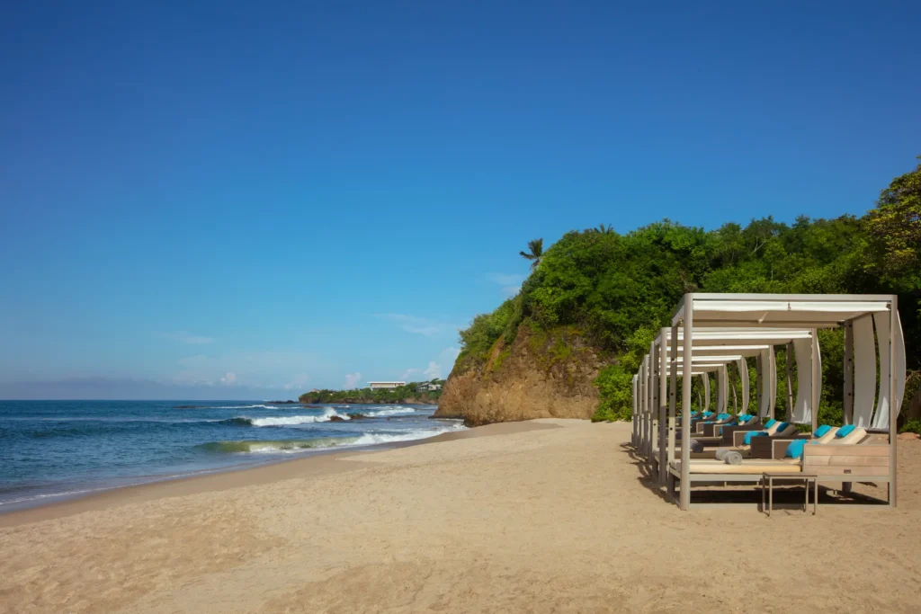 Beachfront Bali beds with canopy seating and ocean views at Dreams Bahia Mita.