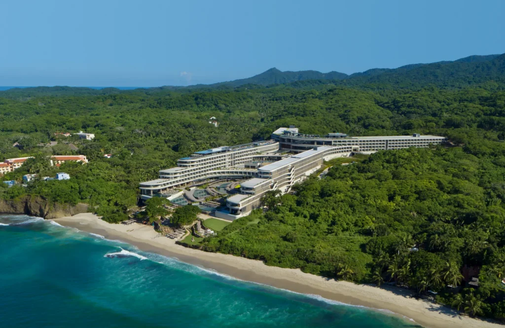 Wide aerial view of Dreams Bahia Mita along the coastline with ocean waves and jungle landscape.