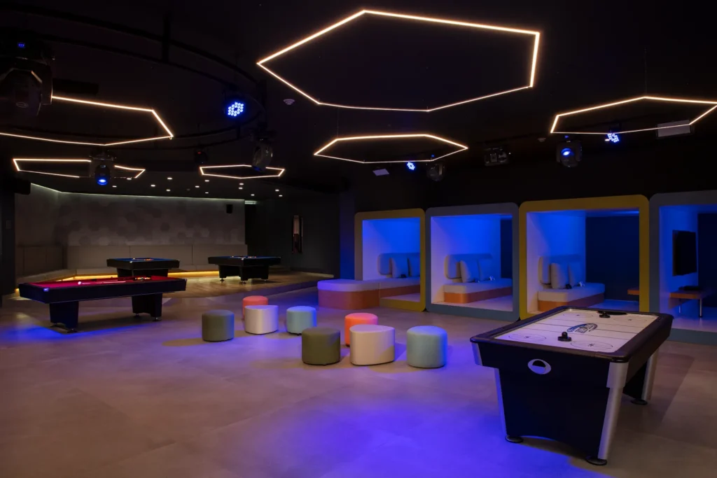Modern teen lounge with neon lighting, gaming tables, and seating pods at Dreams Bahia Mita Core Zone.