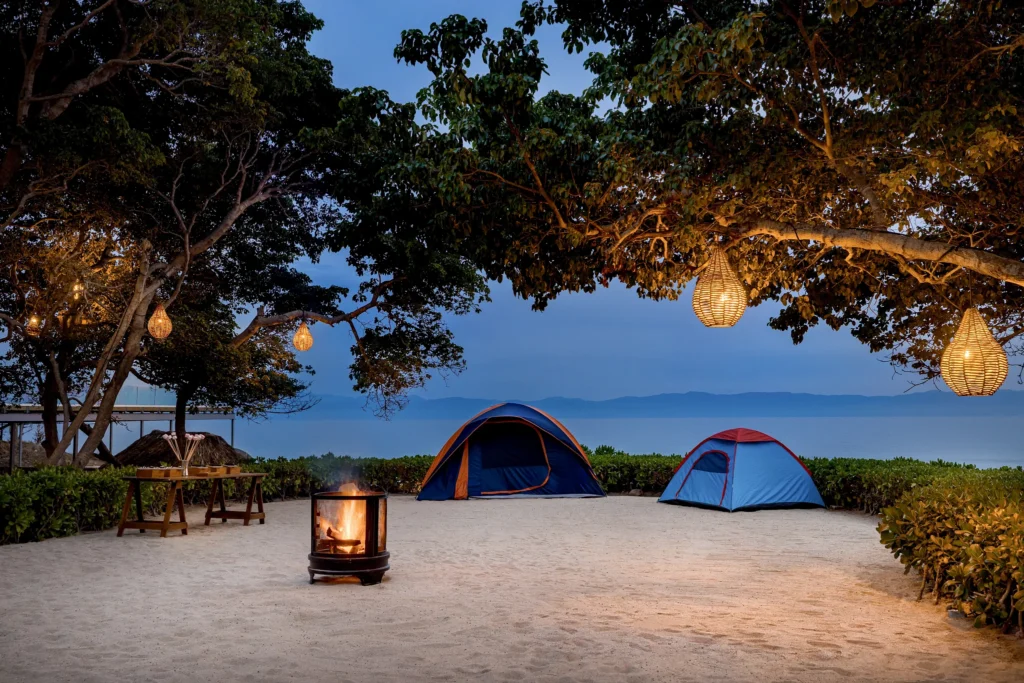 Kids beach campout setup with tents and bonfire under trees at Dreams Bahia Mita Explorer’s Club.