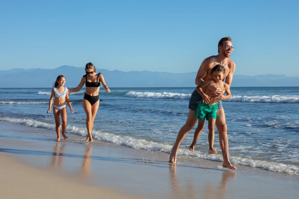 Family playing and running along the shoreline at Dreams Bahia Mita beach.