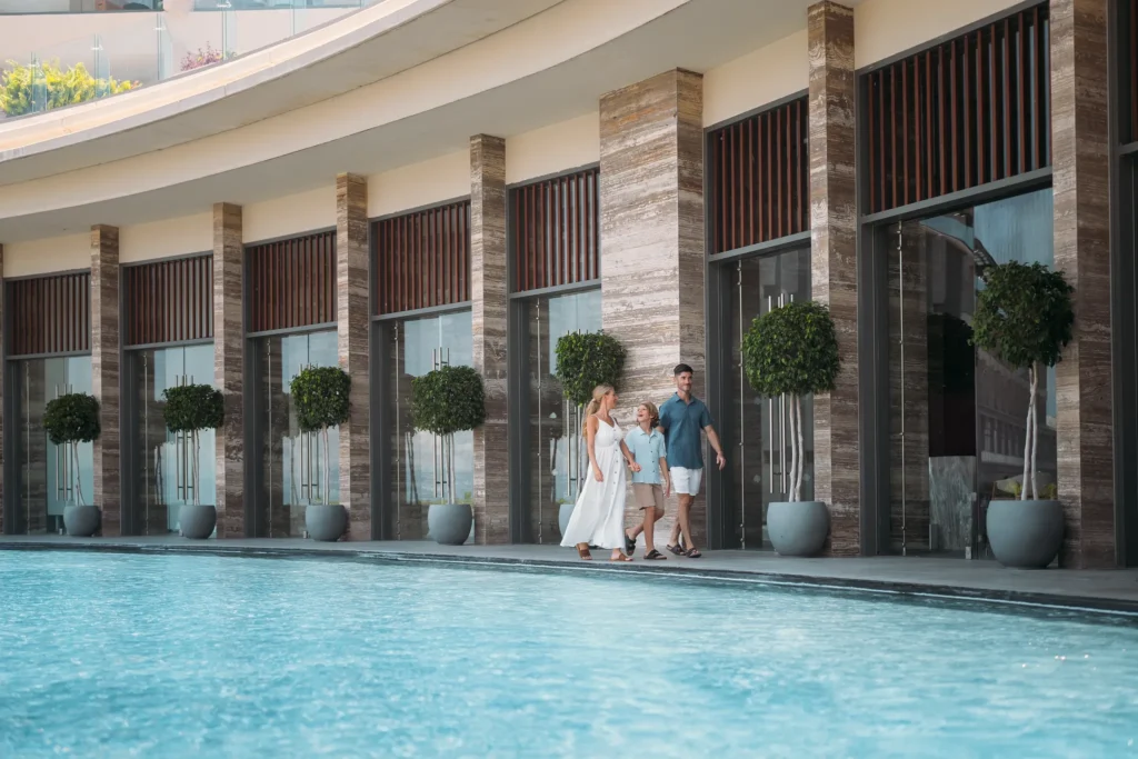 Family walking along poolside walkway near resort building at Dreams Bahia Mita.