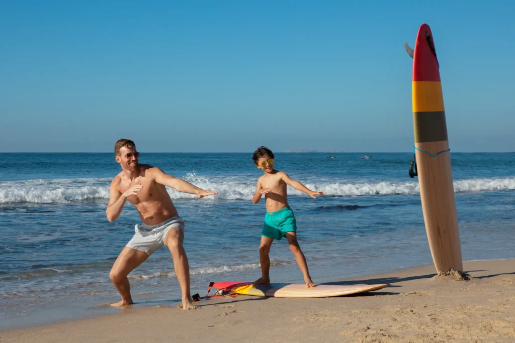 Father and son practicing surfing on the beach with surfboards at Dreams Bahia Mita.