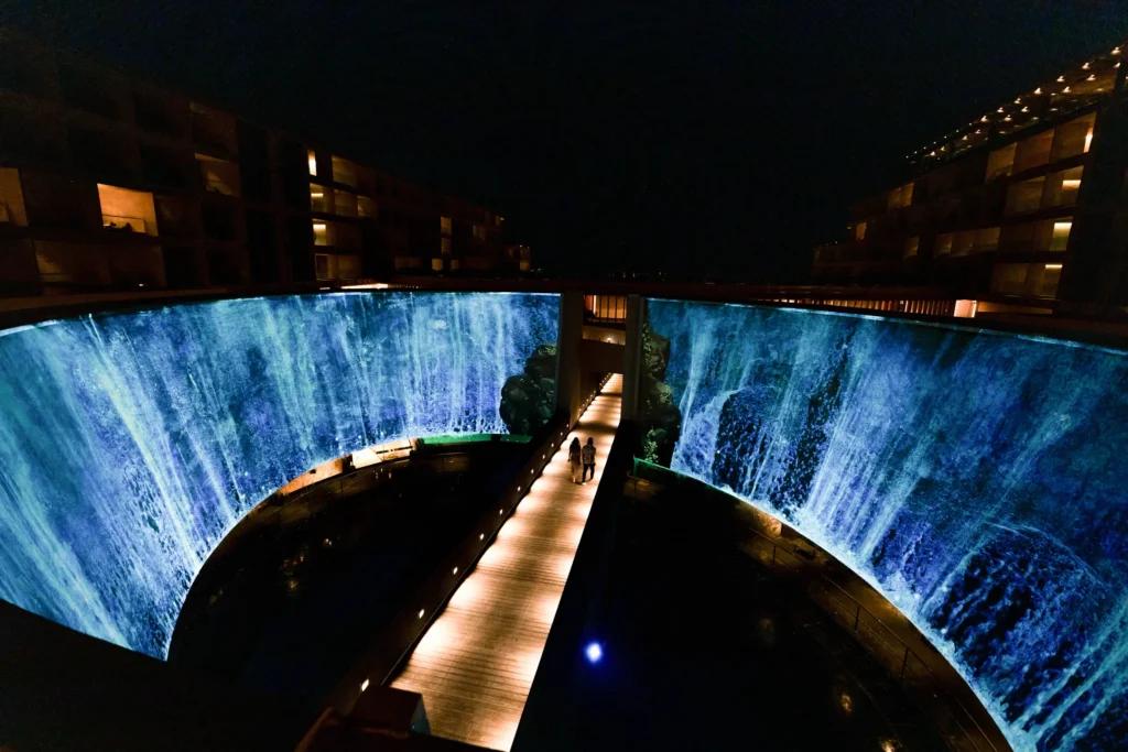 Illuminated water feature wall with cascading light effects at night at Dreams Bahia Mita resort.