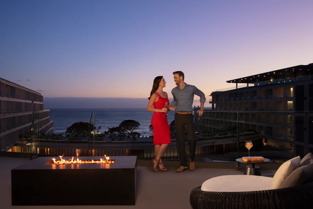 Couple enjoying sunset drinks by fire pit with ocean view at Dreams Bahia Mita.