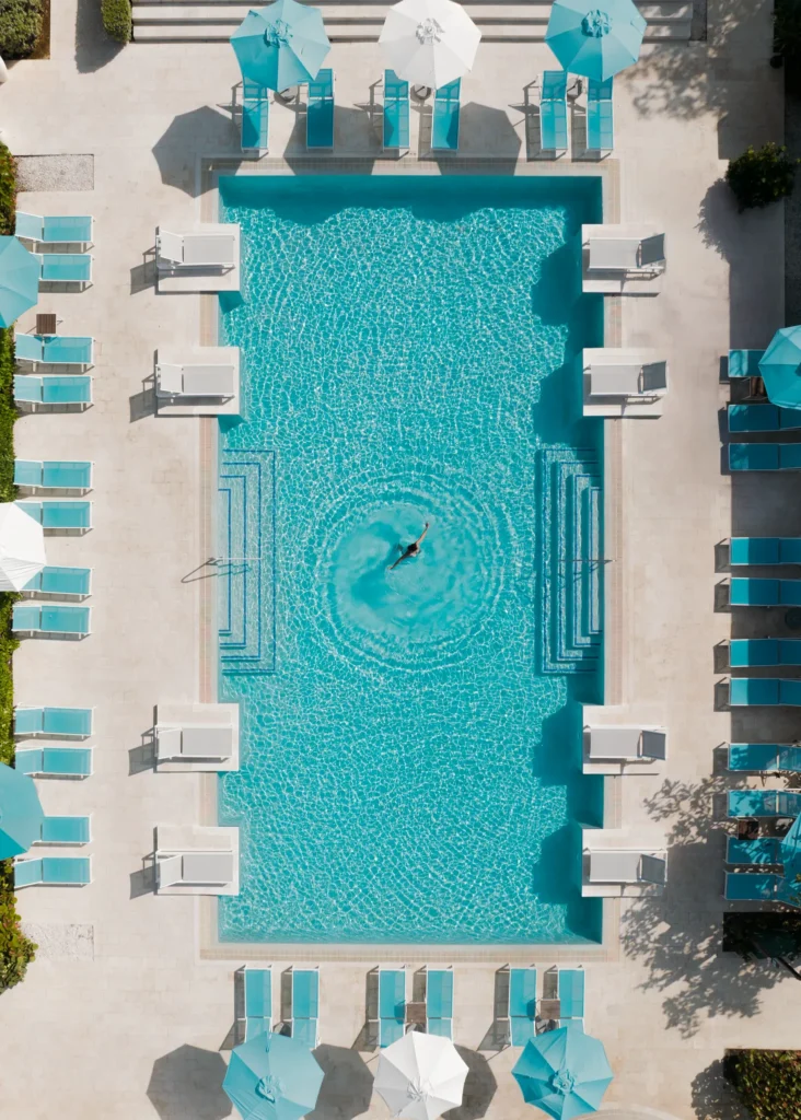 Aerial view of a resort pool with lounge chairs and umbrellas at Dreams Cap Cana Resort & Spa.