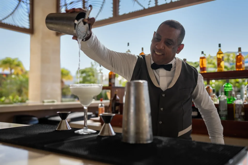 Bartender pouring a cocktail at a bar inside Dreams Cap Cana Resort & Spa.