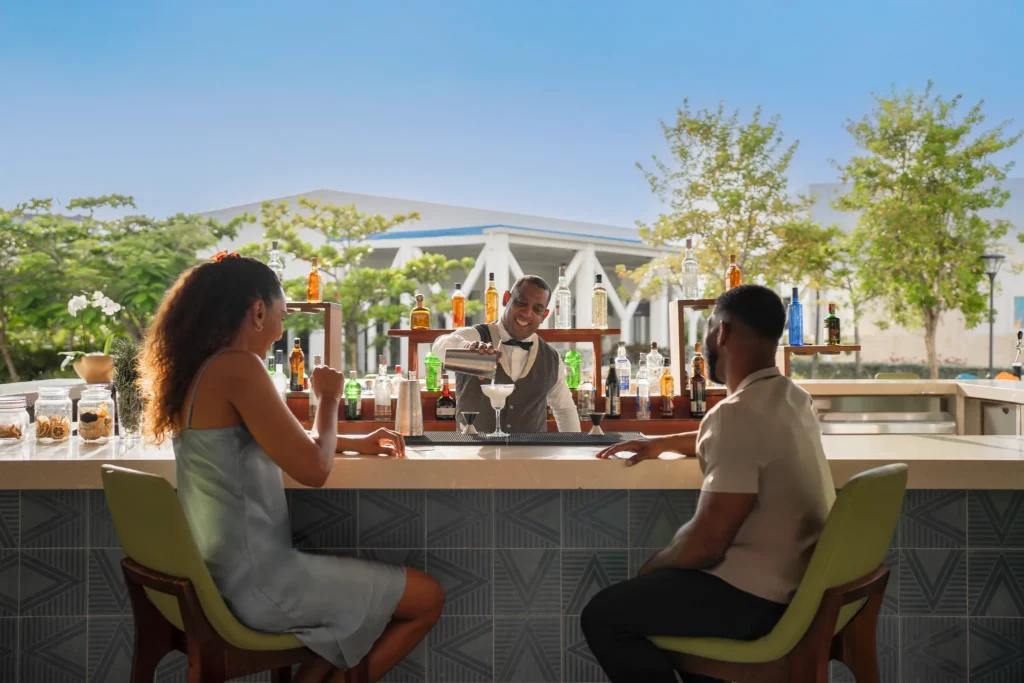 Bartender serving cocktails to guests at an outdoor bar at Dreams Cap Cana Resort & Spa.