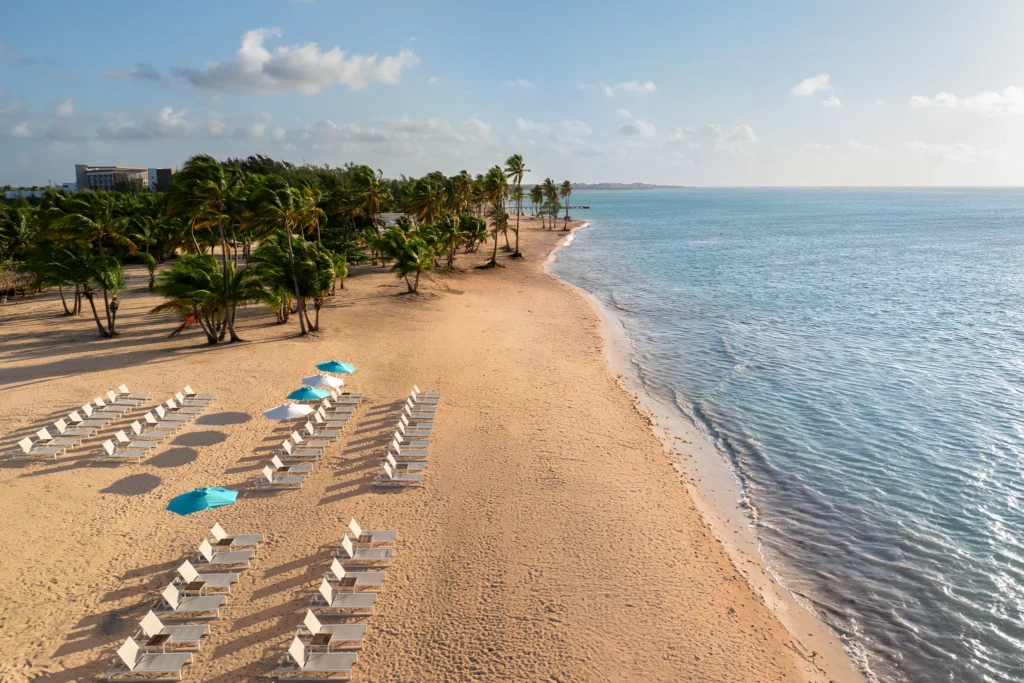 Aerial view of pristine beach with lounge chairs and turquoise Caribbean water at Dreams Cap Cana Resort & Spa in Punta Cana.