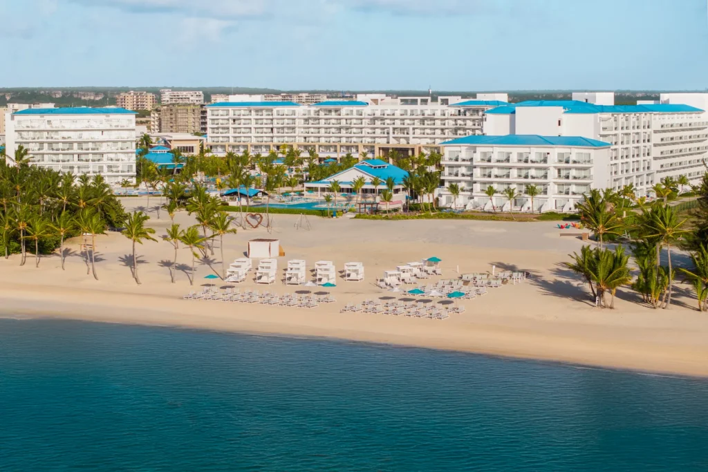 Aerial view of Dreams Cap Cana Resort & Spa beachfront with lounge chairs and white sand in Punta Cana.