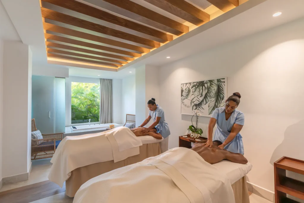 Couple enjoying side-by-side massages in a spa treatment room at Dreams Cap Cana Resort & Spa.