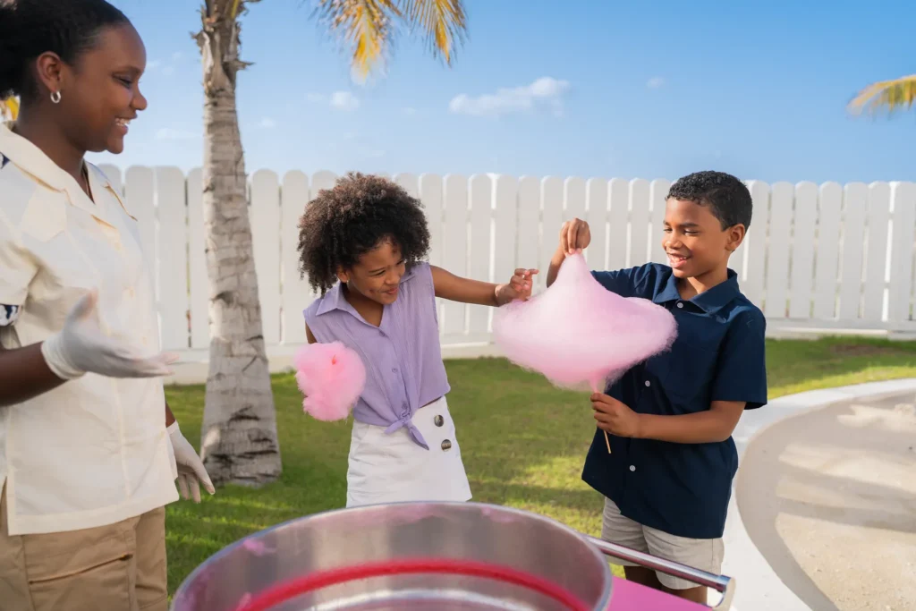 Kids enjoying fresh cotton candy outdoors at Dreams Cap Cana Resort & Spa kids activities area.