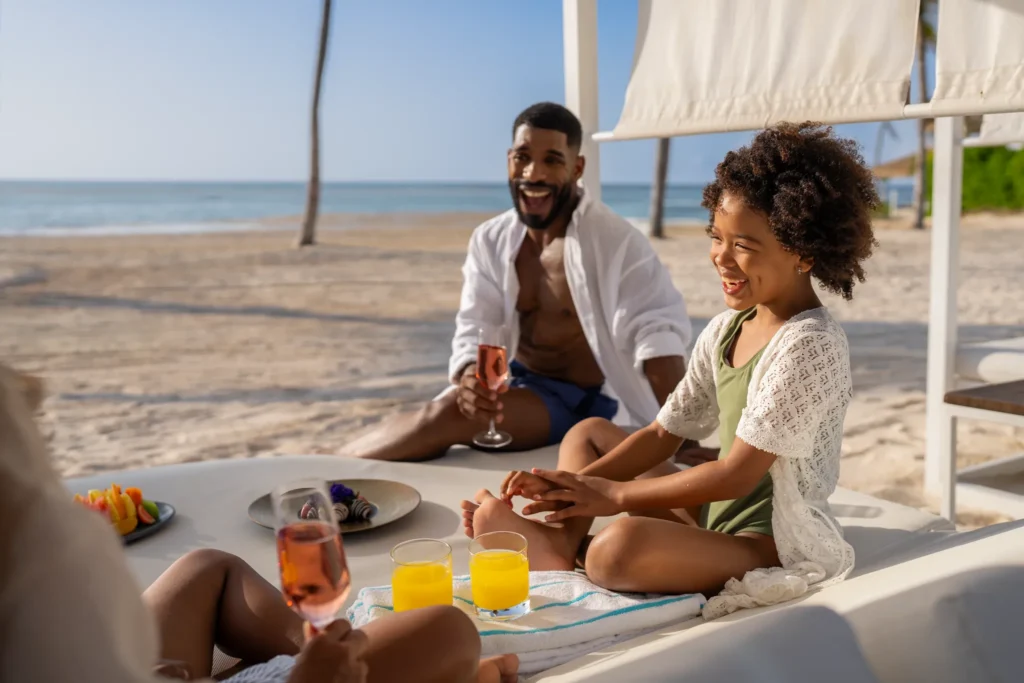 Family relaxing on a beach cabana with drinks and snacks at Dreams Cap Cana Resort & Spa in Punta Cana.