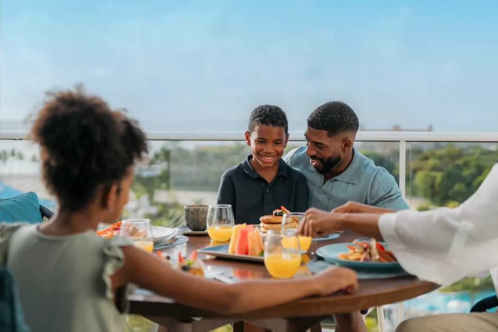 Family enjoying breakfast with ocean views on a private terrace at Dreams Cap Cana Resort & Spa.