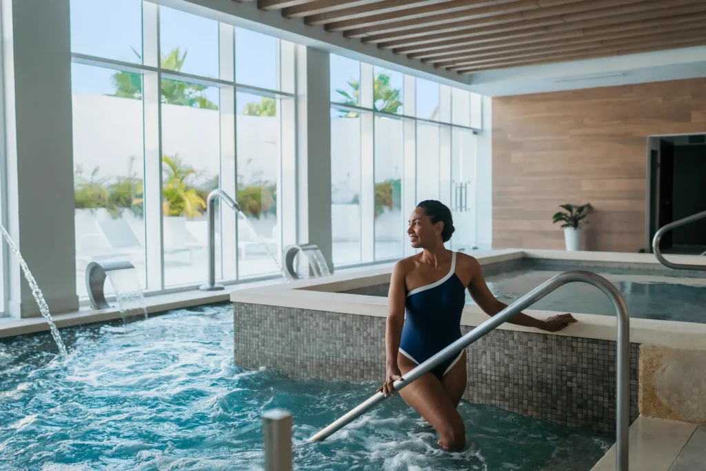 Woman relaxing in a hydrotherapy pool at Dreams Cap Cana Resort & Spa spa facility.