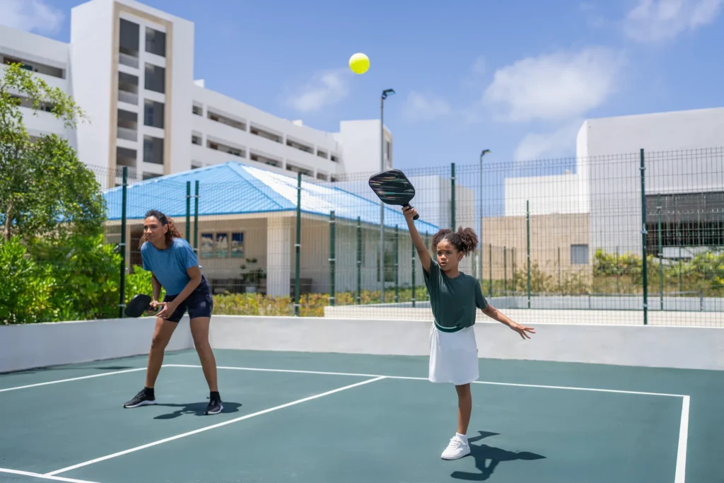 Child playing pickleball on a sunny court at Dreams Cap Cana Resort & Spa in Punta Cana.