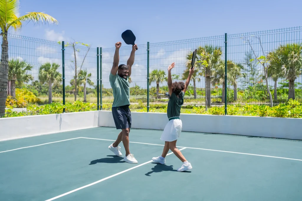 Father and daughter celebrating a pickleball game at Dreams Cap Cana Resort & Spa sports courts.