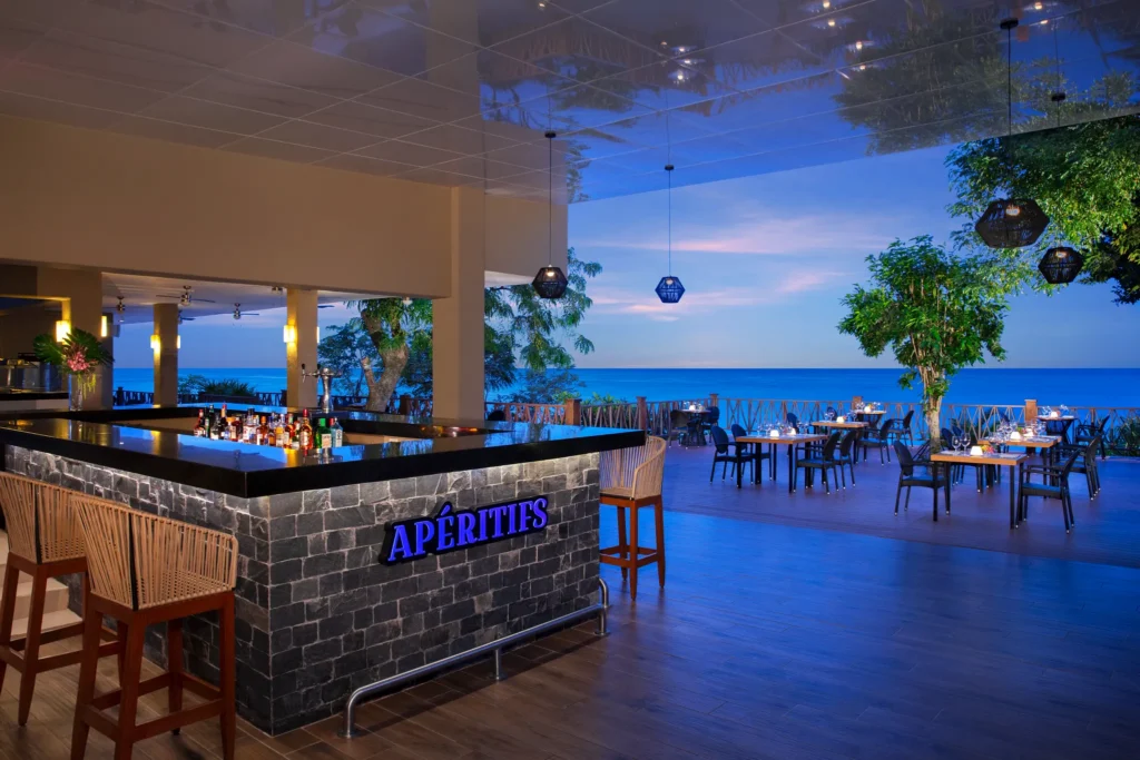 Apéritifs ocean view bar at Dreams Cozumel Cape Resort & Spa featuring an open-air terrace, sunset sea views, and stylish lounge seating.
