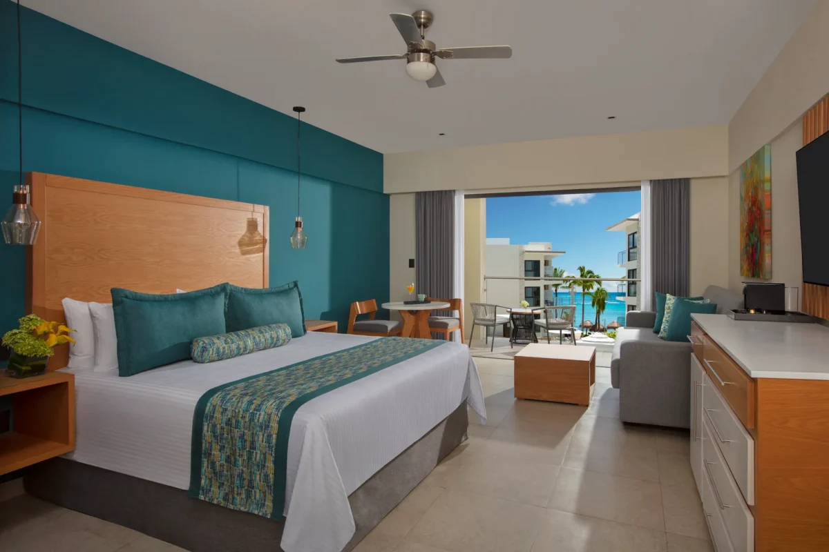 Preferred Club Family Suite with king bed and balcony at Dreams Cozumel Cape Resort & Spa overlooking the ocean and pool.